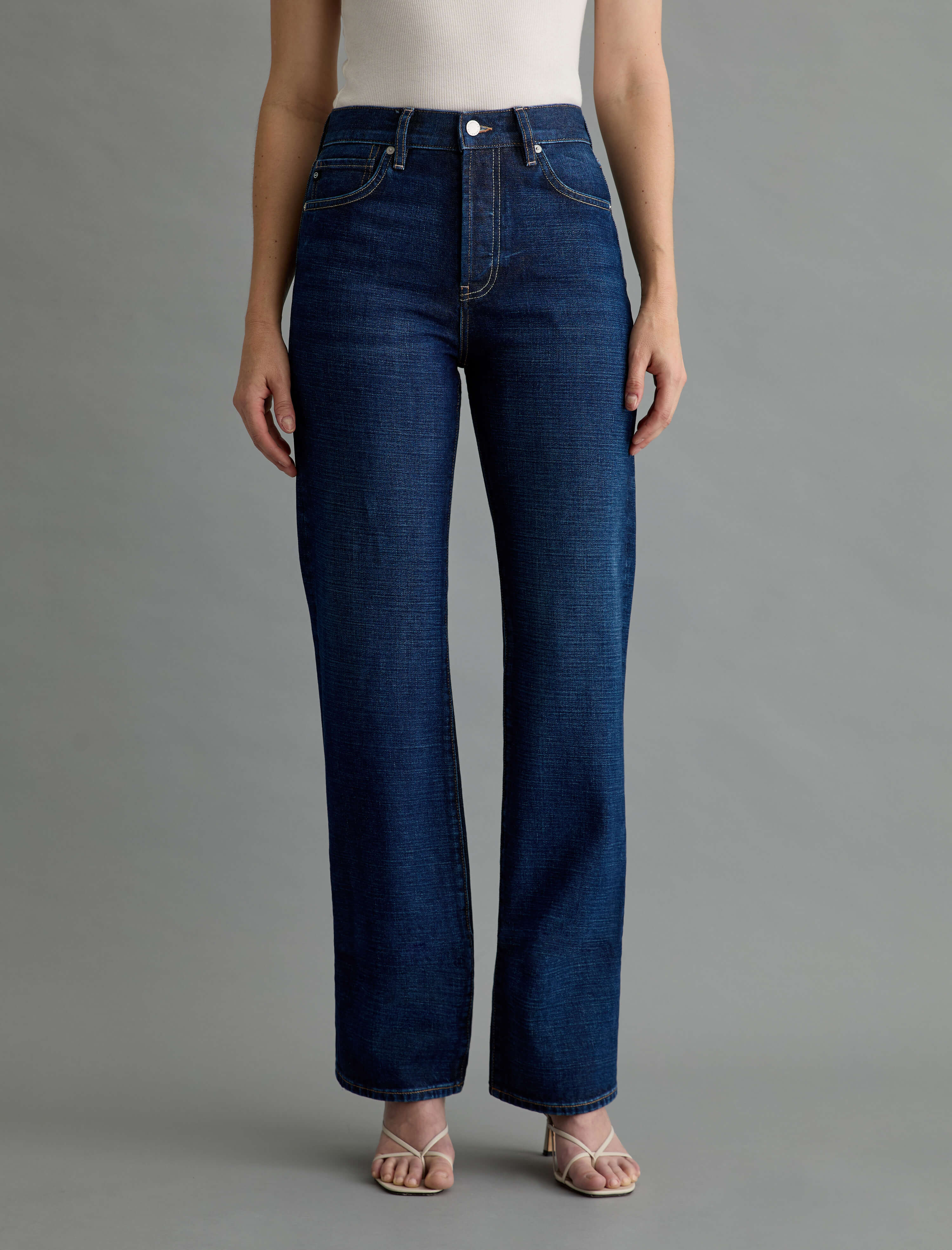 Person wearing dark blue jeans on a gray background