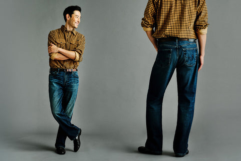 A model is shown wearing dark blue jeans and a brown and yellow gingham shirt