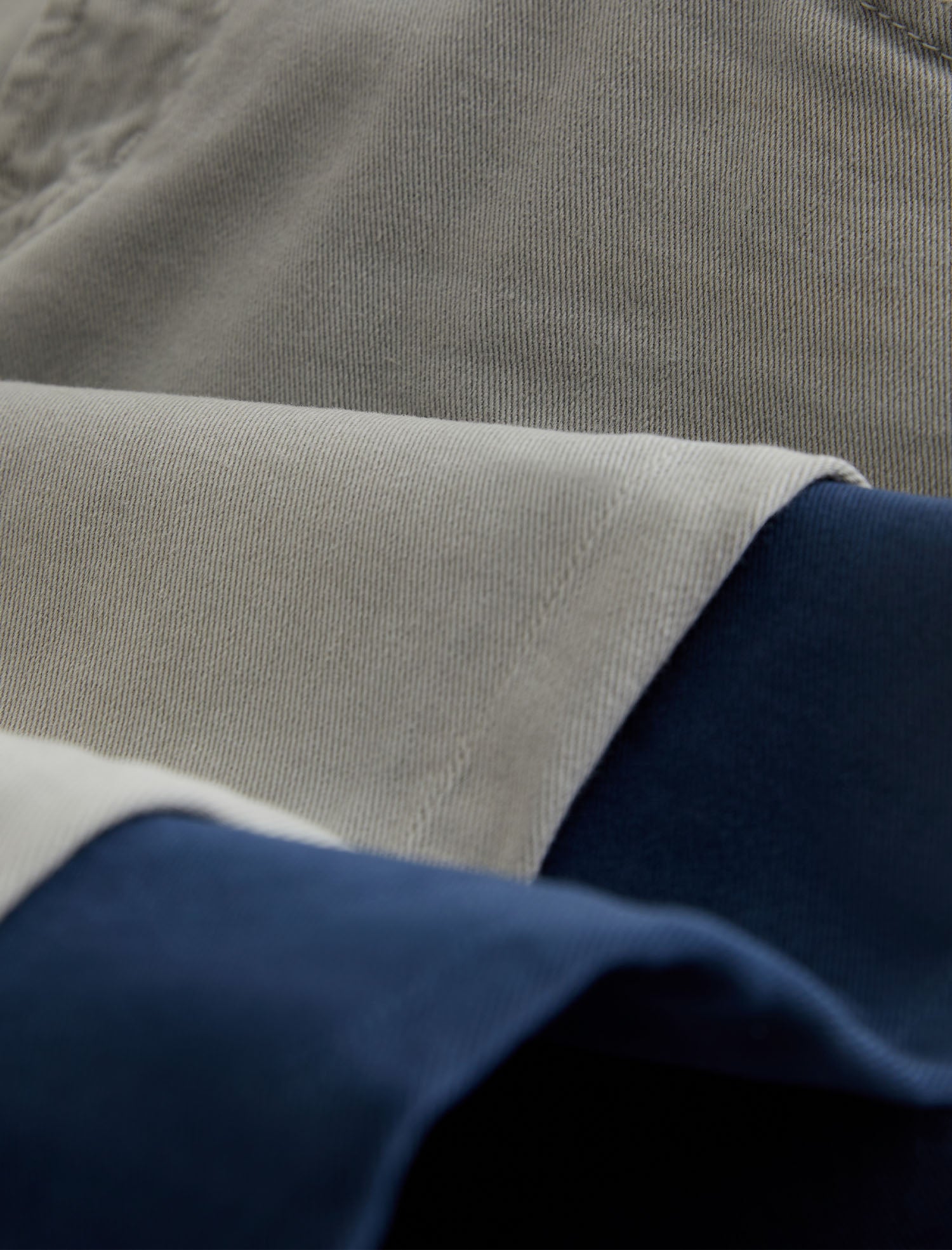 Close-up of folded fabric showing a light beige woven textile layered over a dark navy blue material.