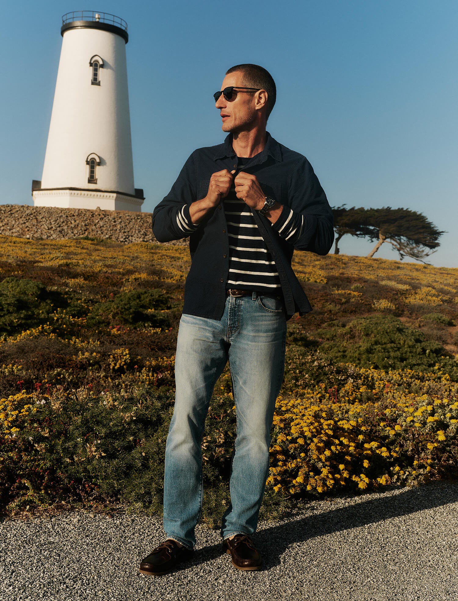 Man standing in front of a lighthouse with a clear blue sky