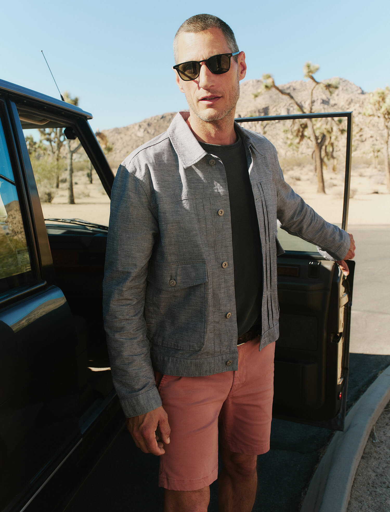 Man standing next to an open car door in a desert setting