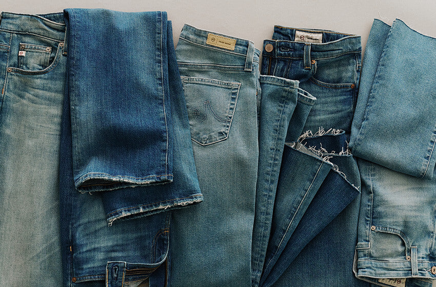Stack of folded blue jeans on a neutral background