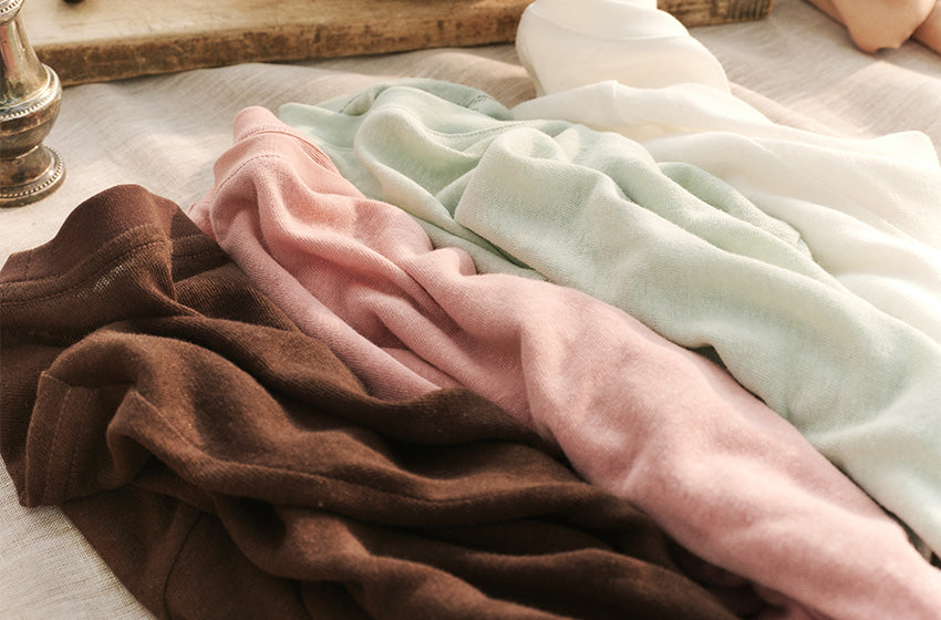 Folded fabric in brown, pink, and white on a textured surface.