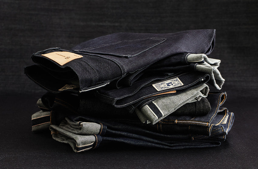 Stack of folded jeans on a black background