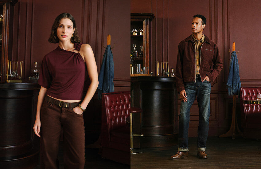 A split-screen lifestyle image showing two models in a dark, elegant bar or lounge setting. The left model wears a dark burgundy asymmetrical top and brown trousers, while the right model wears a brown suede jacket over a plaid shirt with blue jeans.
