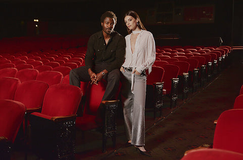 Two people sitting in a theater with red seats