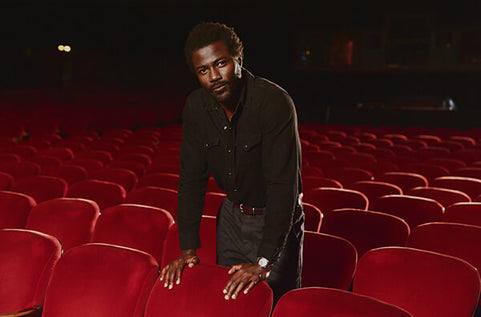 Man in a black shirt standing in an empty theater with red seats.