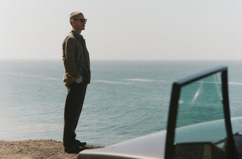 Man standing by a car overlooking a scenic ocean view