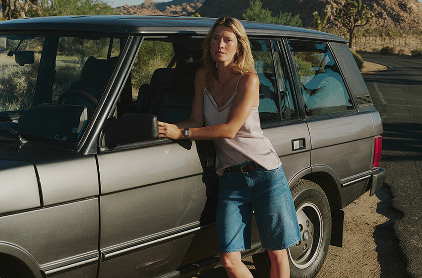 Woman standing next to a car in a desert-like setting