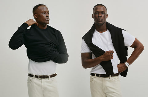 Two men modeling black and white outfits against a plain background