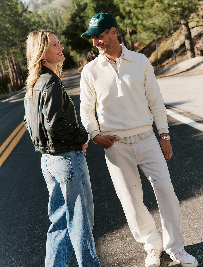 Two people standing on a road with trees in the background