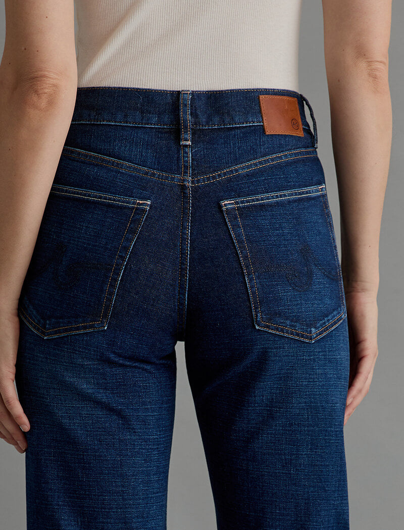 Person wearing blue jeans with a gray background