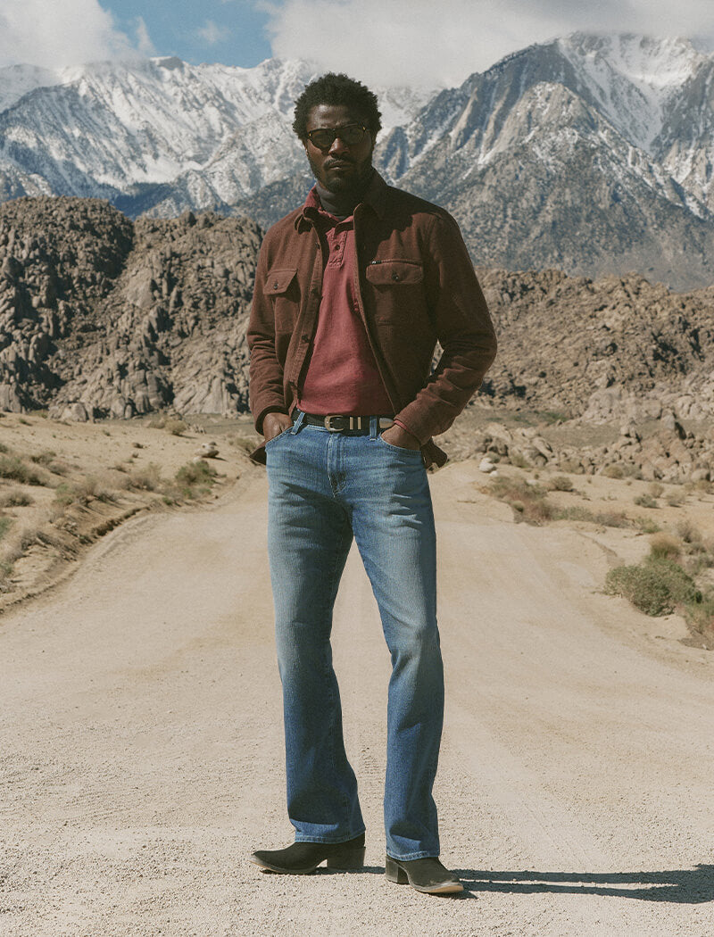 Man standing on a dirt road with mountains in the background