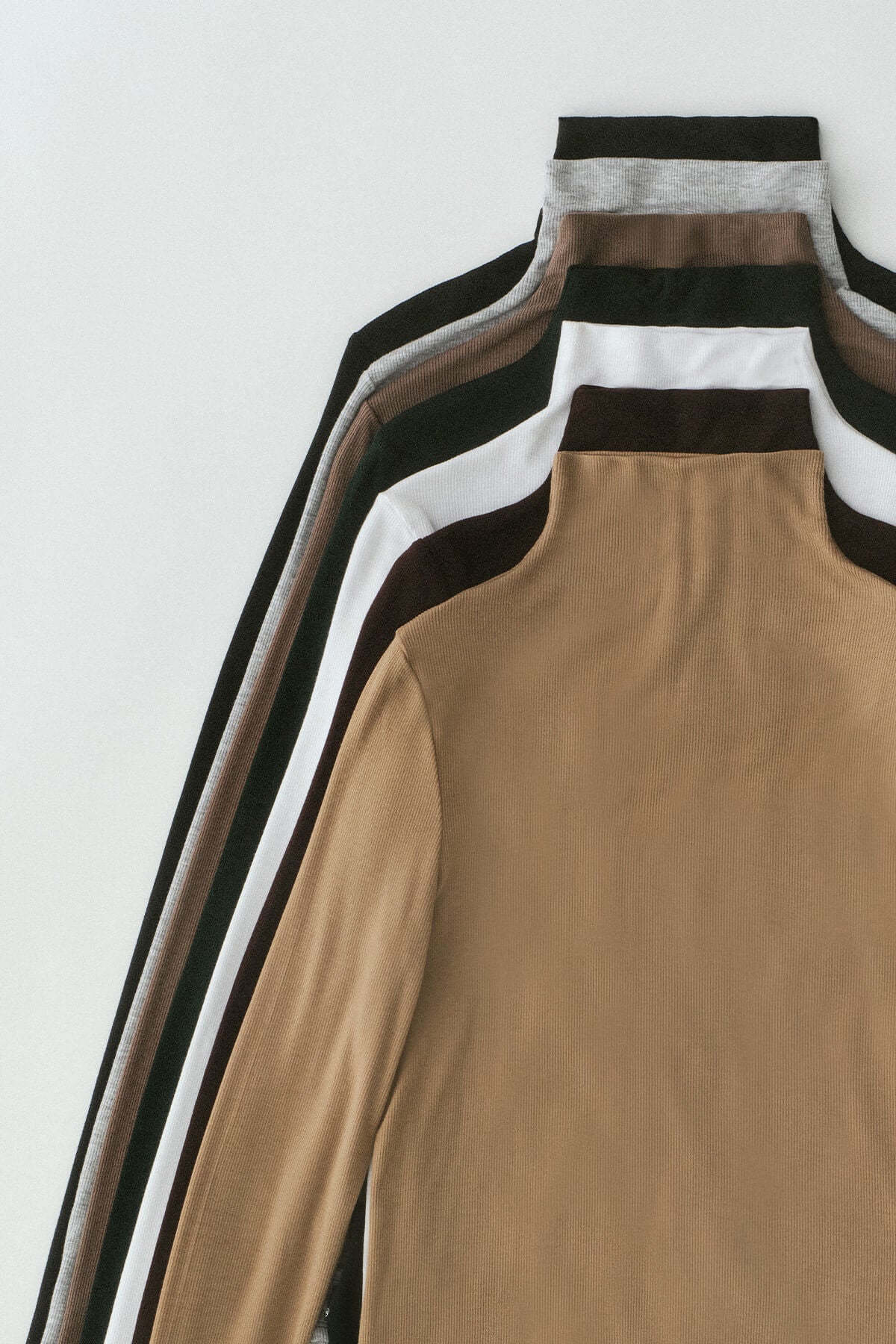 Stack of brown long-sleeve shirts with different collar designs on a white background
