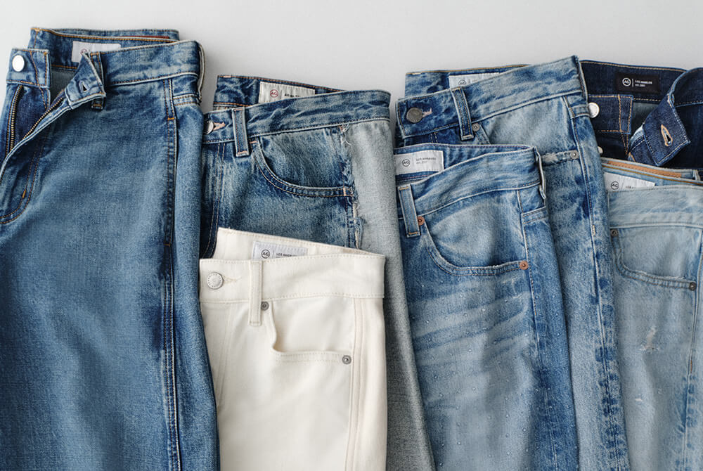 Stack of blue jeans and a white pants on a light gray background