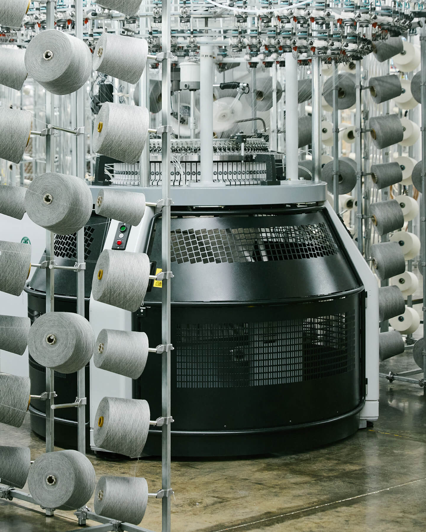 Textile production machine with spools of thread in a factory setting