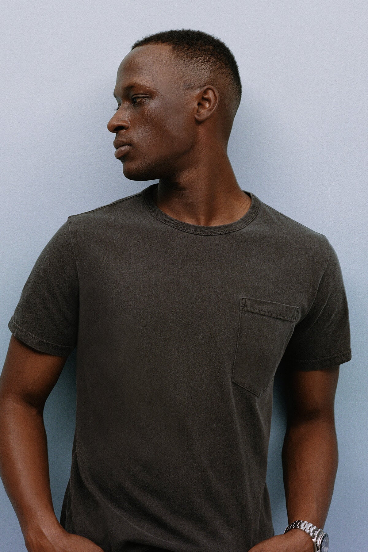 Man wearing a dark gray t-shirt against a light blue background