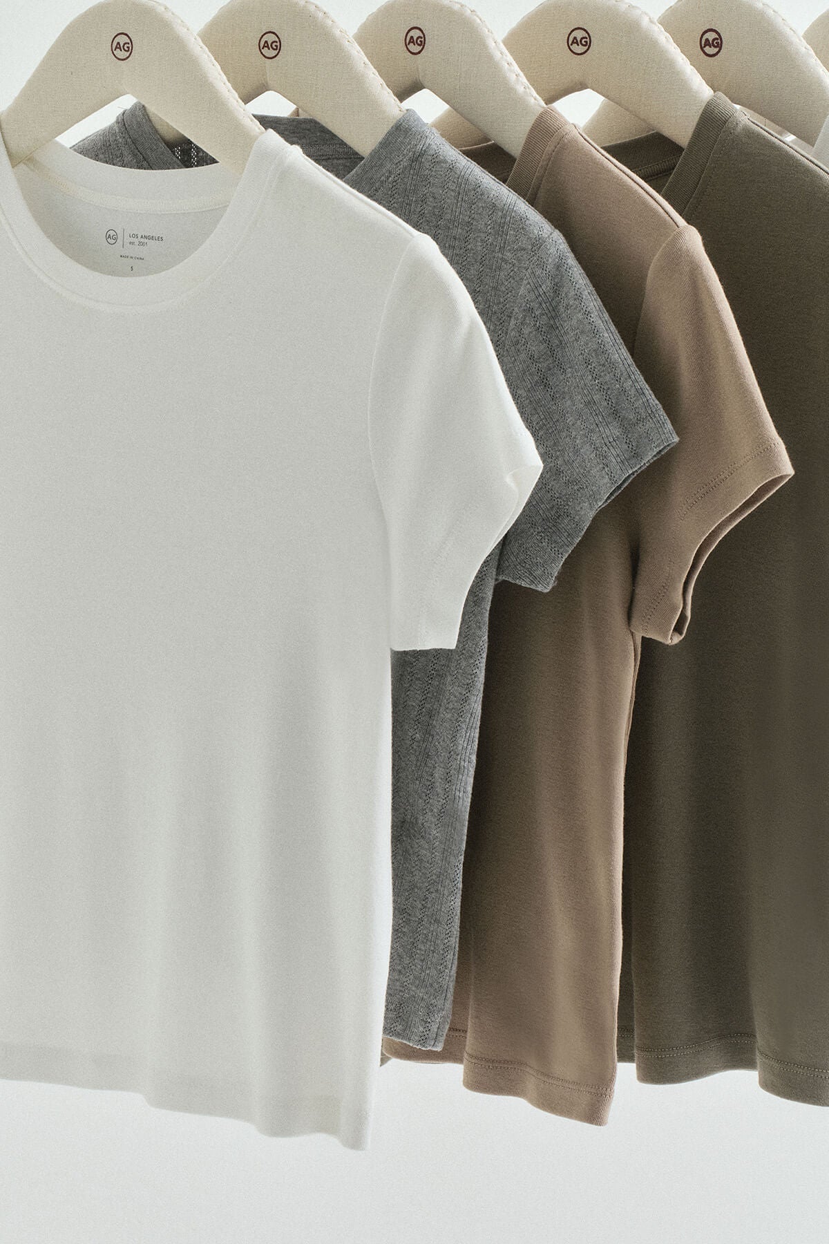 Row of plain t-shirts in various colors hanging on a rack.