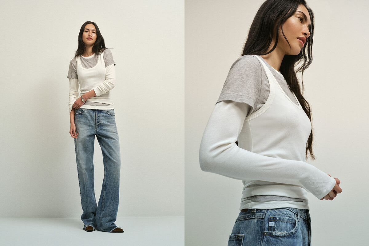 Two women wearing matching outfits of white long-sleeve shirts and blue jeans on a plain background.
